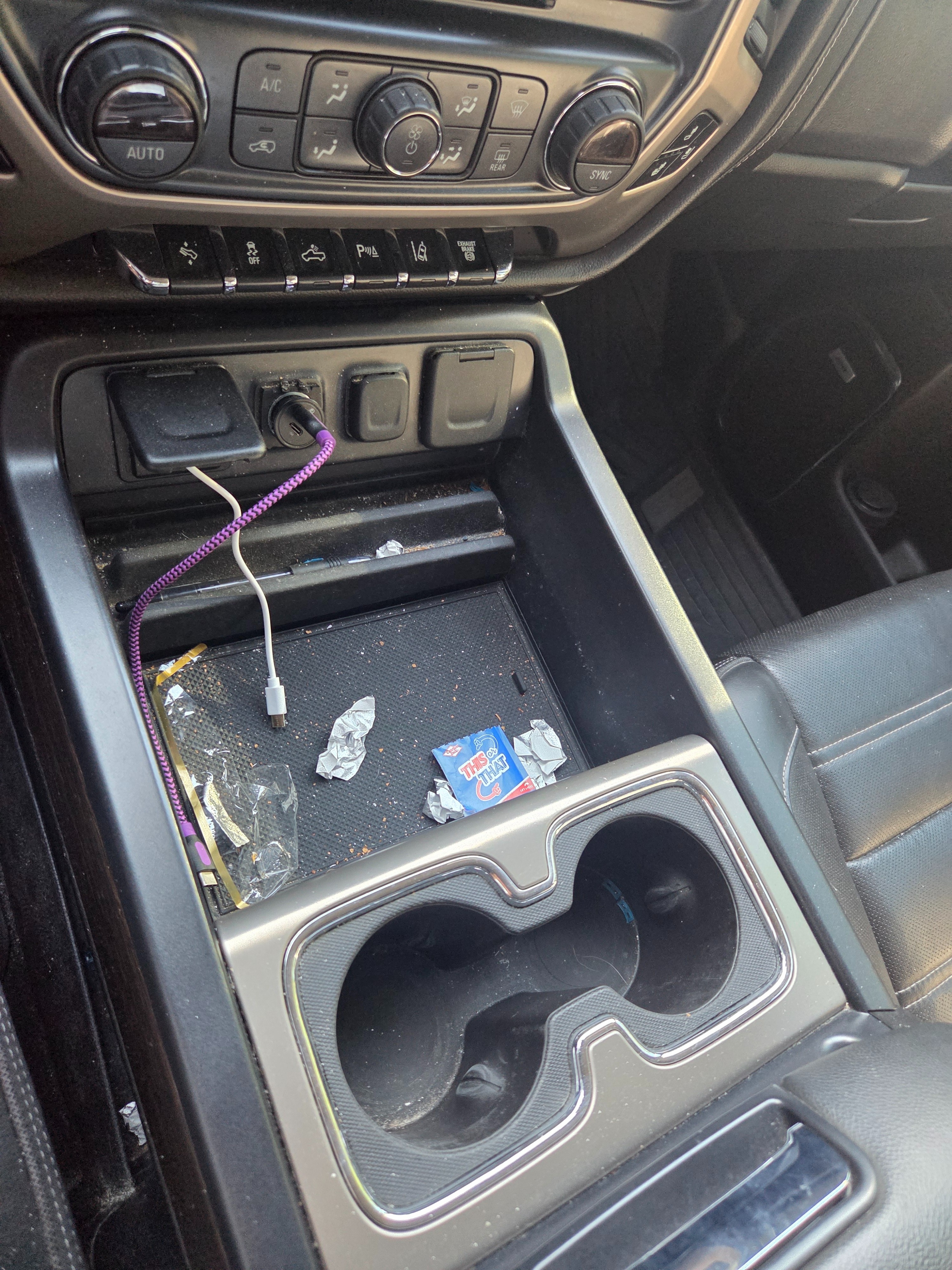 Cluttered GMC truck center console with trash, wrappers, and exposed wires before interior detailing
